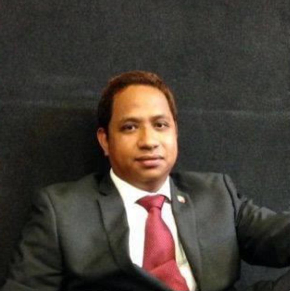 Ronald Baruelo smiling in a red plaid shirt and tortoise shell glasses